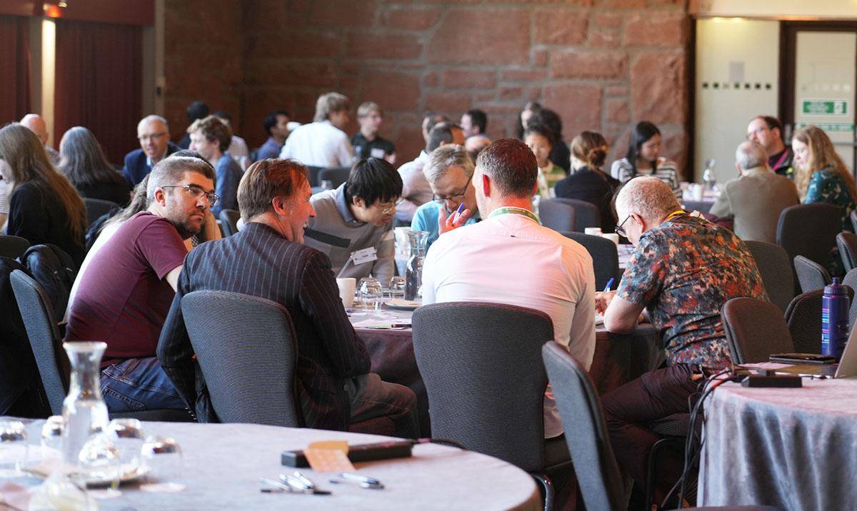 Photo shows group-working session with audience seated at tables