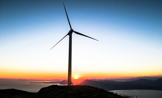 Photo shows single wind turbine at sunset